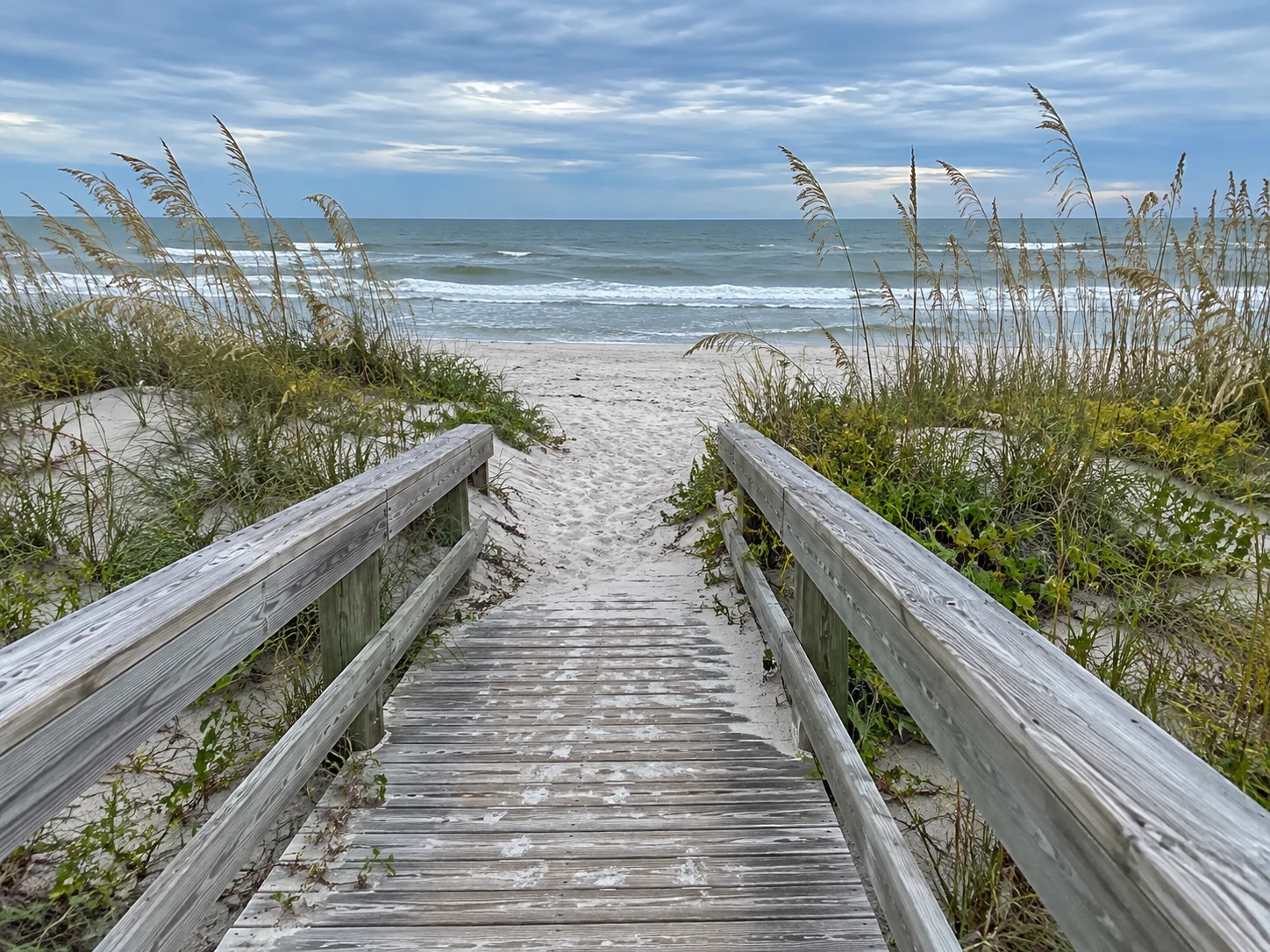 A weathered Atlantic Beach access walkway through sea oats toward the ocean