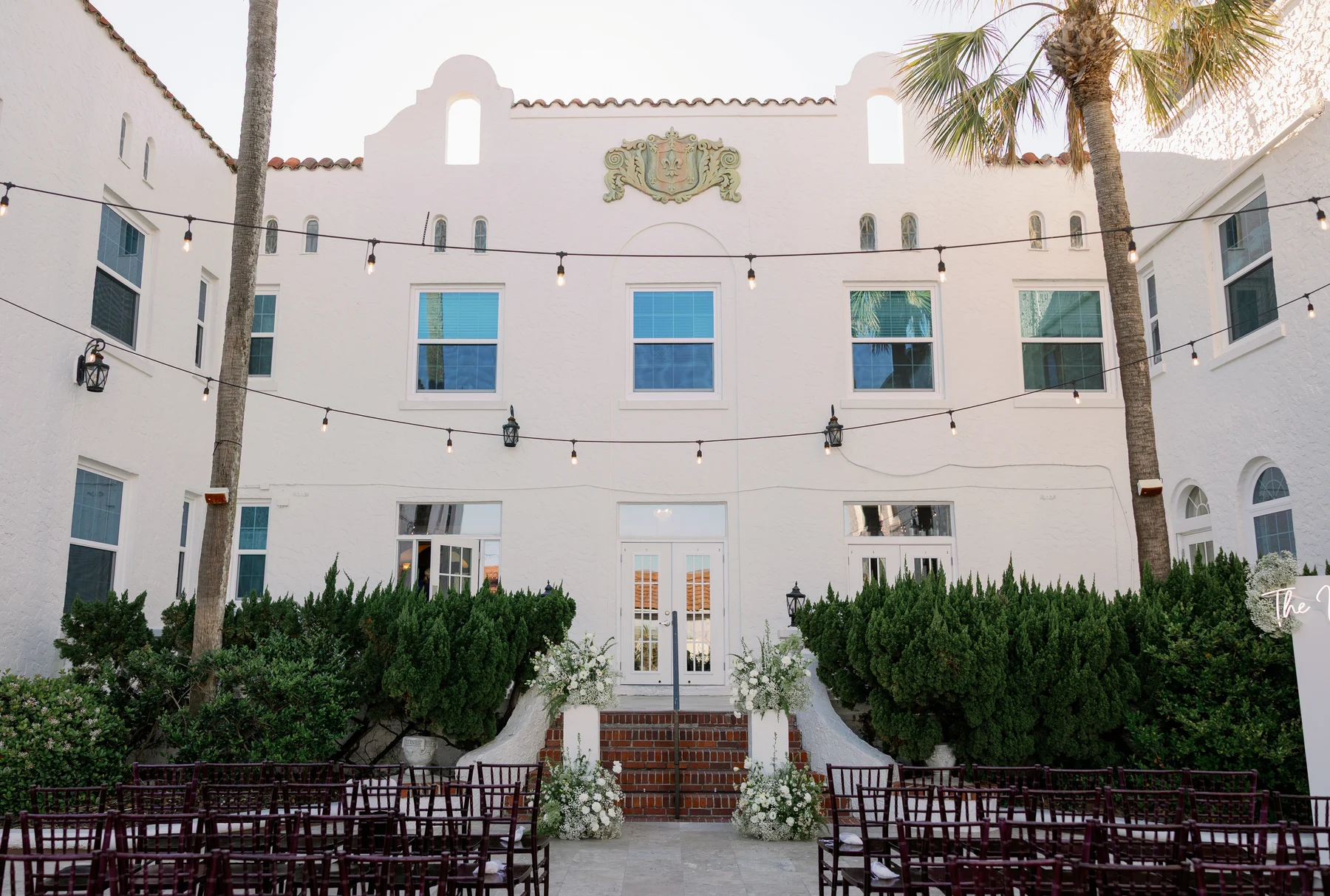 Casa Marina Hotel’s actual courtyard, with white stucco walls, palm trees and ceremony chairs